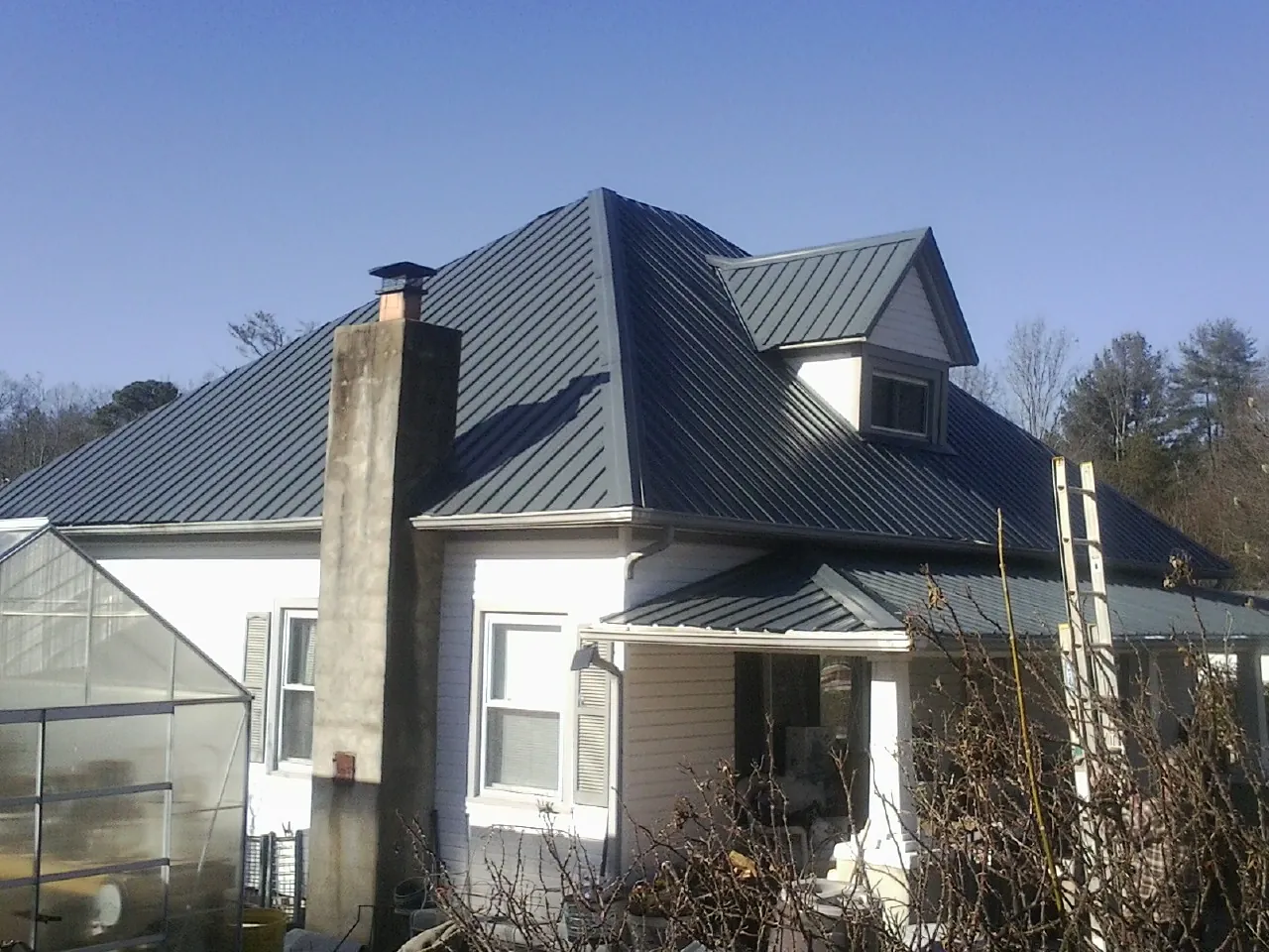 Dark blue standing seam metal roof on a white farmhouse with dormer — Slate & Tile Roof Repair by Roofing Brothers in Lake Stevens