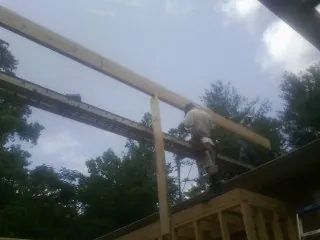 Carpenter setting a ridge beam over a new addition frame — Ice Dam Removal by Roofing Brothers in Lake Stevens