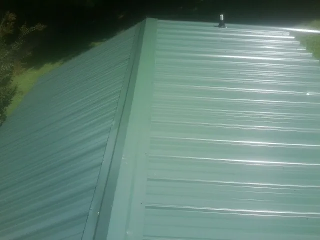 New green metal panels meeting at the ridge of a roof — Flat Roof Repair work by our crew in Lake Stevens