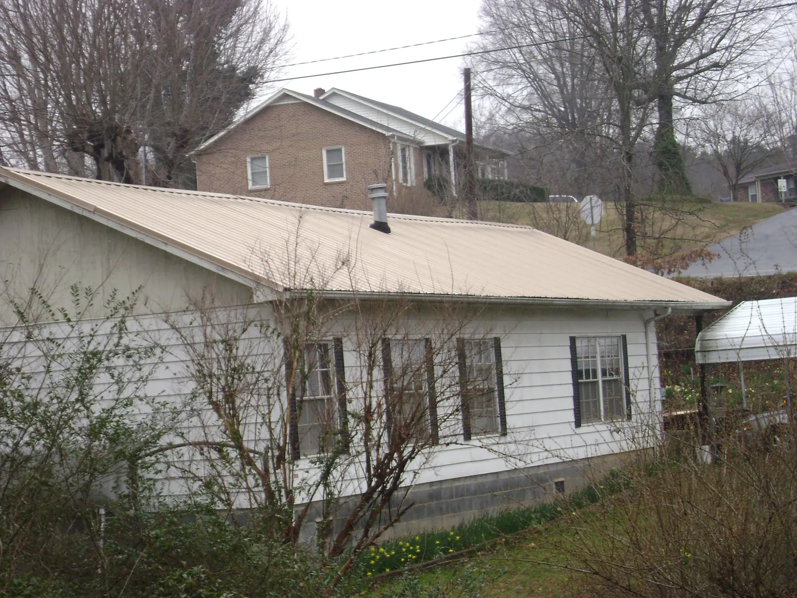 Tan metal roof on a white sided house set into a hillside — Commercial Roofing by Roofing Brothers in Lake Stevens