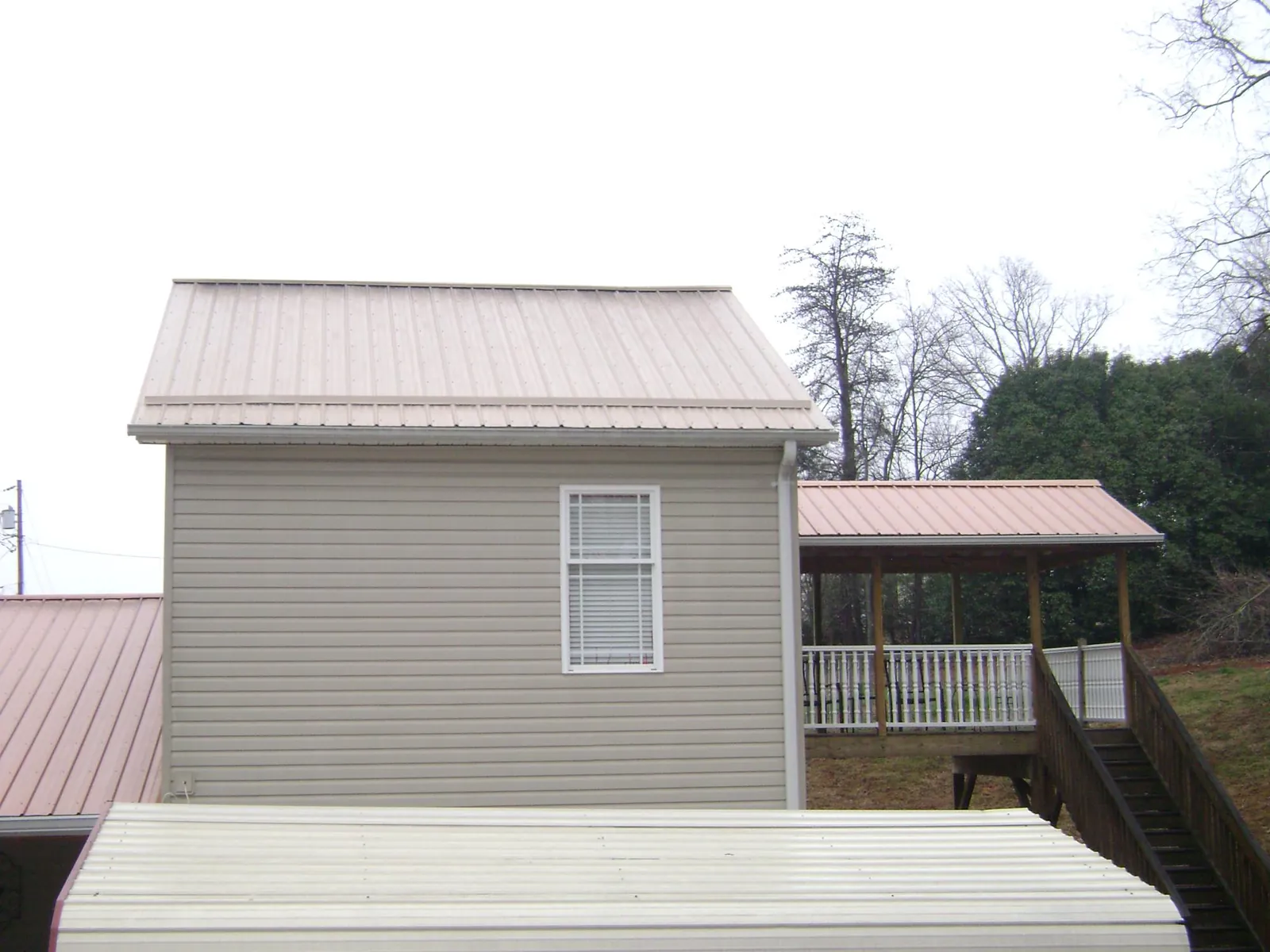 Tan metal roofs on a two story addition and attached porch, from a Roof Replacement job in Lake Stevens