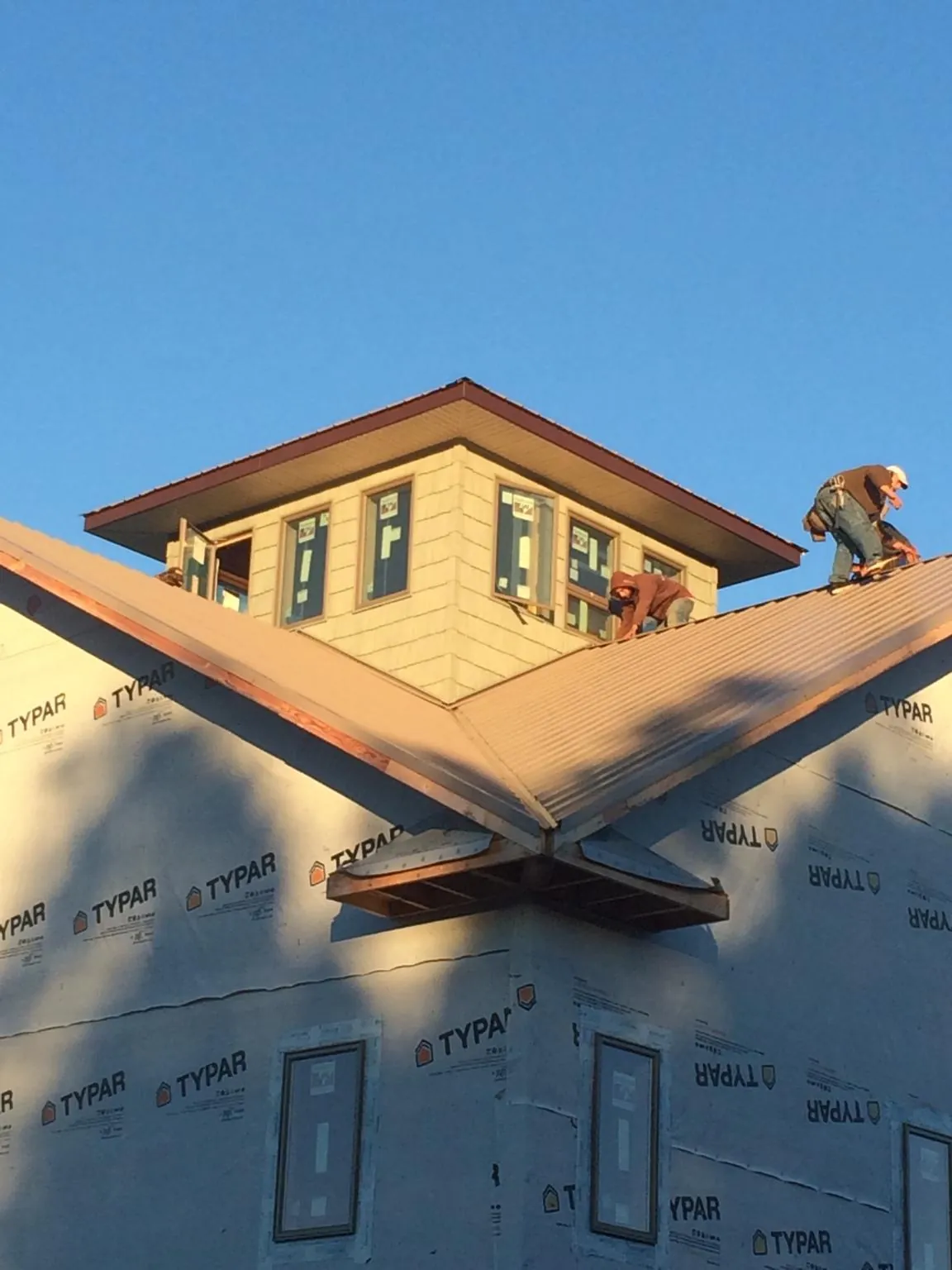 Roofers working around a rooftop cupola on a new metal roof at sunset — Roof Waterproofing in Lake Stevens by Roofing Brothers